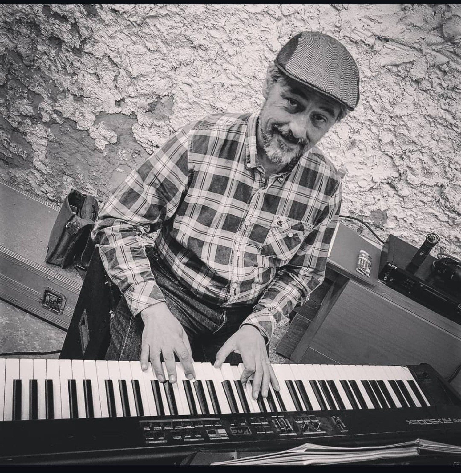 Teclista con gorra tocando el piano, en blanco y negro